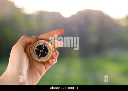 Woman holding compass in nature, closeup. Navigational instrument Stock Photo