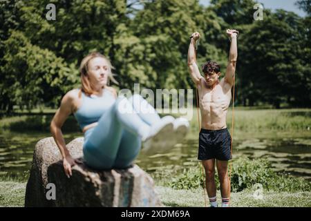 Young man and woman performing outdoor calisthenics exercises together in a park Stock Photo