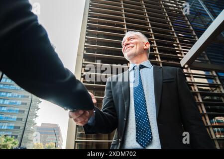 Confident and successful business men walking down the staircase, talking about the corporate finance. Office colleagues on a stairway having a conversation. Middle aged executive males discurssing. High quality photo Stock Photo