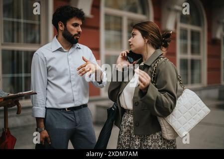 Two business professionals engaged in a serious conversation outside a building Stock Photo