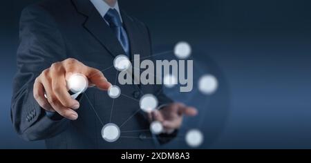 A businessman in a suit interacting with a futuristic virtual interface. His finger is pointed towards a glowing node, representing digital connectivi Stock Photo