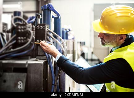 Portrait of engineer controlling machine in modern industrial factory. Manufacturing facility with robotics, robotic arms and automation. Storing Stock Photo