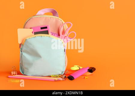 Backpack with school supplies on orange background Stock Photo