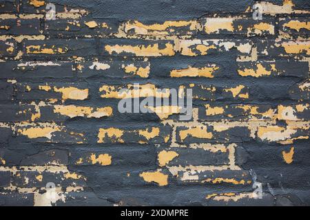 Old black brick wall with peeling paint Stock Photo