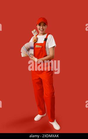 Female painter with color palettes and paint roller on blue background ...