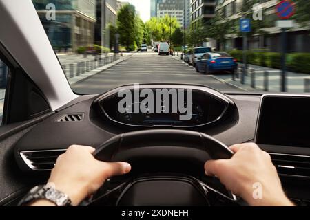 Driving car, view from driver's seat. Man holding hands on steering wheel, closeup Stock Photo