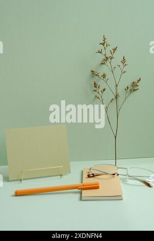 Workspace note, memo pad, eyeglasses, pen, dry flower on mint green desk background Stock Photo