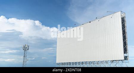 Outdoor Billboard Mockup with Blue Sky and Clouds. Advertising erected outside against a cityscape, copy space for text. Large horizontal blank sign o Stock Photo