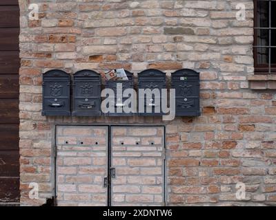 Castellarquato, Italy - June 22nd 2024 Silver Flag rally ,  Five vintage grey metal mailboxes hanging on a brick wall of an old building, one is full Stock Photo