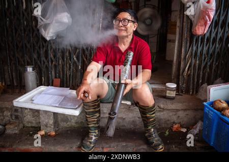 A man smokes a traditional bamboo pipe Stock Photo