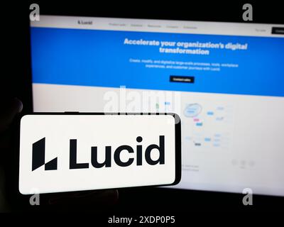 Person holding smartphone with logo of US collaboration suite company Lucid Software Inc. in front of website. Focus on phone display. Stock Photo