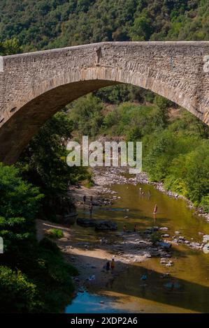 People bathing in river under bridge crossing the Gorges du Doux, Scenic railway, Chemin de Fer du Vivarais, Ardeche, France Stock Photo