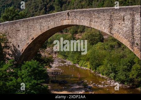 People bathing in river under bridge crossing the Gorges du Doux, Scenic railway, Chemin de Fer du Vivarais, Ardeche, France Stock Photo