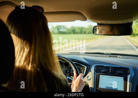 Woman driving car on country road at sunset. Back view of female driver in vehicle Stock Photo