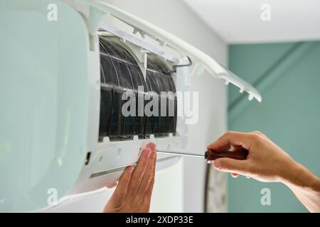 Air conditioner maintenance. Male technician repairs home climate system in living room. Man is cleaning filters of conditioner Stock Photo