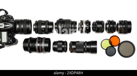A diverse group of camera lenses, ranging from vintage manual focus to modern autofocus, are displayed alongside a digital SLR camera on a white backg Stock Photo