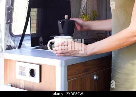 woman preparing coffee in the kitchen of a camper van Stock Photo