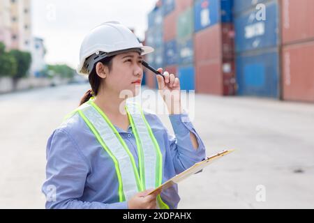 Asian Customs worker Thinking gesture work in logistic industry. Port officer working in shipping container yard. Stock Photo