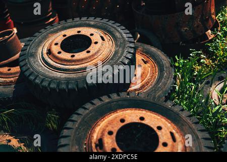 Old worn tires and rusty vehicle wheel rims on dump ground, selective focus Stock Photo