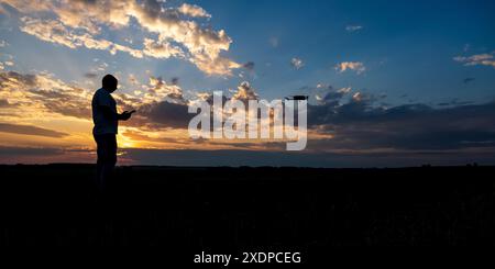 silhouette of man controlling  drone on sunset background Stock Photo