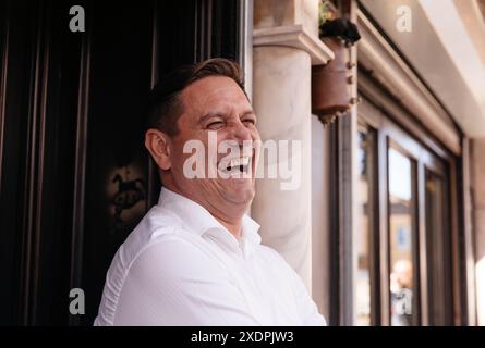 Man in a white shirt laughing joyfully while enjoying coffee Stock Photo