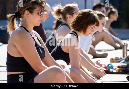 People sitting in meditation during outdoor yoga class on sunny day Stock Photo