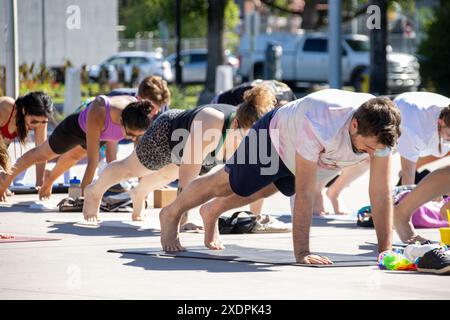 Group yoga class outdoors in plank position on sunny day Stock Photo