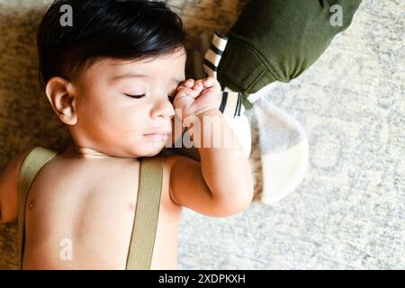 Baby peacefully sleeping on a soft surface with a stuffed toy be Stock Photo