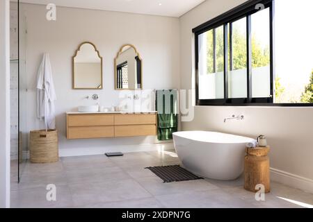Modern bathroom with freestanding bathtub, double sink vanity, and large windows, copy space Stock Photo