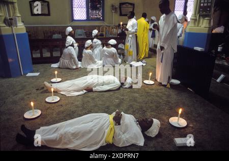 Yoruba UK. The Celestial Church of Christ, the traditional Church of England pews have been removed from this previously unused English church. During a Sunday church service women go into a trance, and lay on the floor. They are 'In Spirit' or 'In Holy Spirit', and wait to receive a message from the Lord. 'Mercyland' which represents the sacred West African beach of Porto Novo (not in picture) is full of people In Spirit.  Islington, London, England 1993 1990s HOMER SYKES Stock Photo