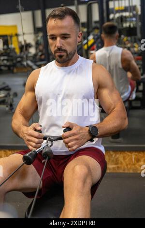 Muscular man in the gym training back sitting on the bench. Stock Photo