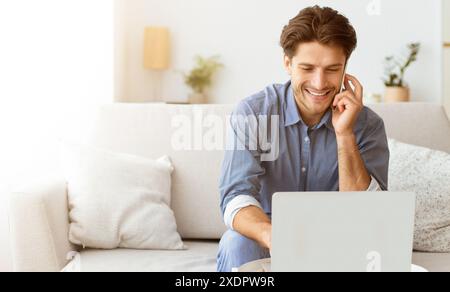 Man Smiling While on Phone Call and Using Laptop Stock Photo
