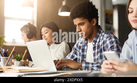 Diverse group of zoomers studying with tech in library Stock Photo