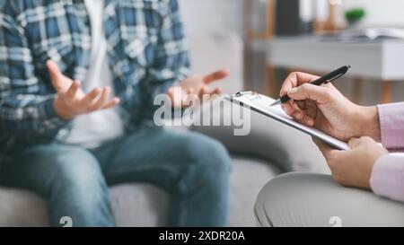 Therapist Taking Notes While Listening to Patient in Counseling Session Stock Photo