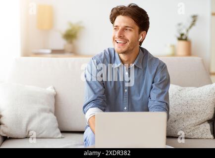 Man Laughing While Using Laptop on Couch Stock Photo