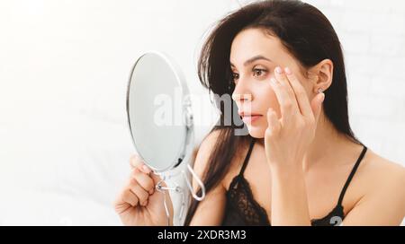 Long-Haired Woman Examining Her Face in Mirror Stock Photo