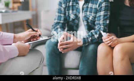 Therapist Taking Notes While Couple Sits on Couch During Session Stock Photo