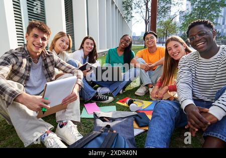 Portrait of a multiethnic group of students sitting on the grass at university to study together. Stock Photo