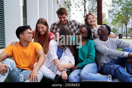 Multiracial group of students gathering outside university campus talking and having fun together. Stock Photo