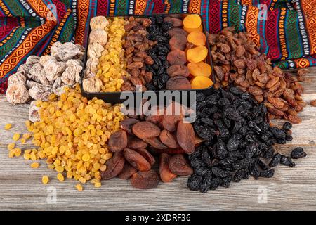 Types of dried fruits. Dried apricots, black and light raisins and dried figs in a gift bag. There are many types of dried fruits in piles on the coun Stock Photo