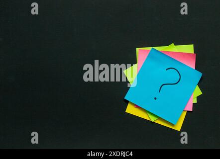 stack of stickers with questions on a black board, questions and idea concept Stock Photo