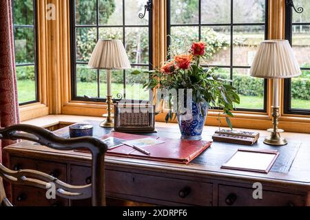 Pair of desk lamps and roses in window of library extension. 16th century Tudor farmhouse, Hertfordshire, England, UK Stock Photo
