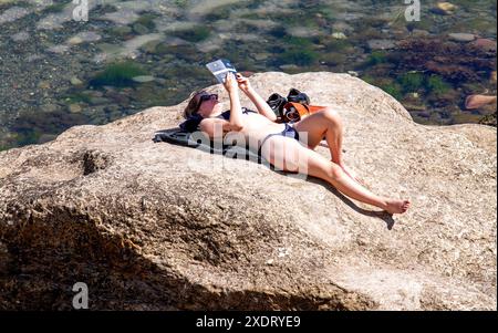 St Andrews, Fife, Scotland, UK. 24th June 2024. UK Weather: St Andrews in Fife, Scotland, has bright sunshine with temperatures reaching 23°C. The hot June weather draws both locals and tourists to Castle Beach where people enjoy the Scottish summer and sunbathe.  Credit: Dundee Photographics/Alamy Live News Stock Photo