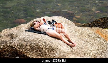 St Andrews, Fife, Scotland, UK. 24th June 2024. UK Weather: St Andrews in Fife, Scotland, has bright sunshine with temperatures reaching 23°C. The hot June weather draws both locals and tourists to Castle Beach where people enjoy the Scottish summer and sunbathe.  Credit: Dundee Photographics/Alamy Live News Stock Photo