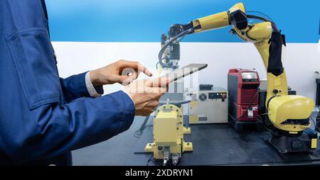 Engineer uses a digital tablet to control robots in a smart factory. Smart industry 4.0 concept.. Stock Photo