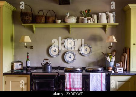 Decorative plates above aga with shelf painted 'Churlish green' in charming Somerset rectory dating from 17th century, South West England, UK. Stock Photo