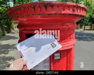 London, UK. 24th June, 2024. A postal vote for the 2024 general election being posted in a letter box in Clapham, Lambeth. Although the elections date is 4 July, people with postal votes who have already made up their minds can vote early, Credit: Anna Watson/Alamy Live News Stock Photo