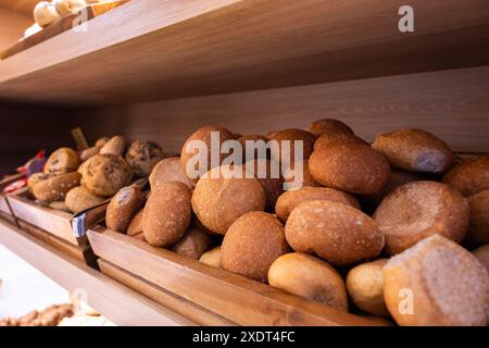 A wooden shelf with a variety of breads, including rolls and bagels. The breads are piled high, creating a sense of abundance and variety Stock Photo