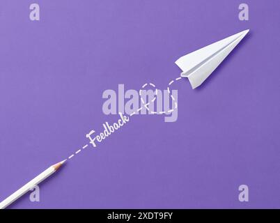 Customer feedback concept. To give feedback. The word Feedback with white crayon and a paper plane on purple background. Stock Photo