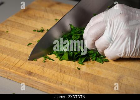 A chef slicing parsley on wooden cutting board. Studio shot Stock Photo